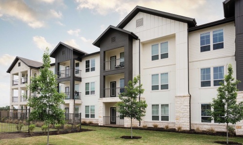 Elegant interior lounge area at 1846 Apartments, Fredericksburg, TX, with modern seating, warm lighting, large windows, and stylish decor in a spacious setting.